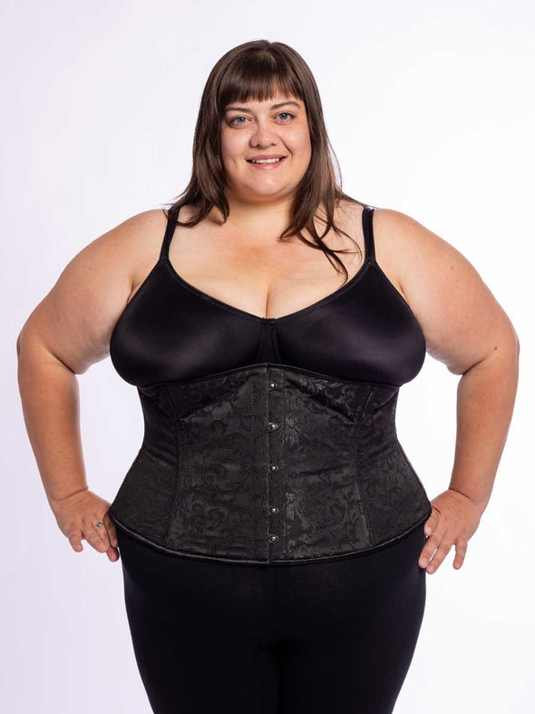 curvy plus size model wearing a black bra and leggings and a black brocade corset for waist training