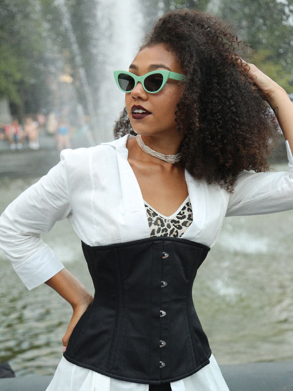Model wearing a white jacket with leopard print tank completeing her outfit with a black cotton steelboned corset