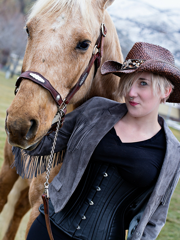 Model walking a horse wearing our underbust 426 longline steel boned black leather corset tops
