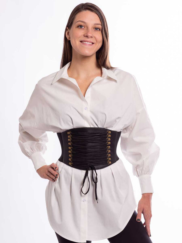 Model wearing a white tunic and black leggings with a wide faux lace up corset belt