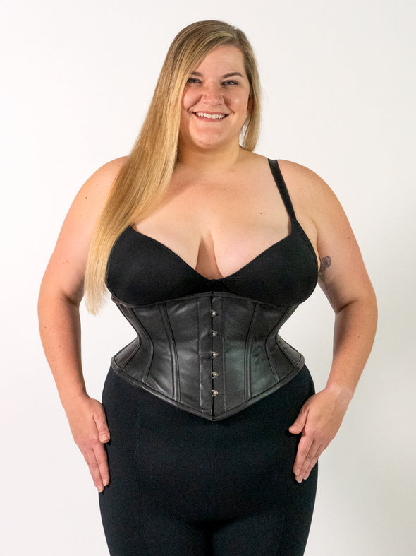 Product shot of a Curvy plus sized model wearing a black bra and black leggings and a leather cs-201 hourglass curve corset