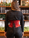 back lace up corset view of a woman with long hair in a lounge wearing a red velvet coset for waist training and fashion with sequin shorts and over the knee boots