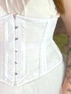 close up detail view of Model standing in fantasy forest wearing a white fairycore dress with a white waspie corset and pearls cs-220 waist training corset for weddings and boudoir shoots