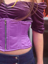 Close up detail view of Sassy cute model wearing a short lilac corset belt with front zipper closure. Standing with one hand on her hip and wearing a short denim skirt and platform shoes