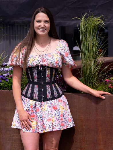cute corset model wearing a floral dress with the cs 411 longline waist training black mesh corset 