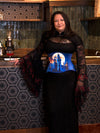 Woman wearing a black lace top and blue corset with a castle design in a bar setting.