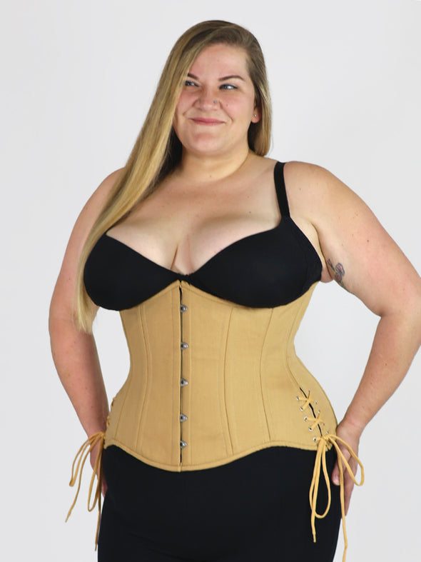 curvy plus size model wearing a beige corset for waist training and fashion over black leggings and bra