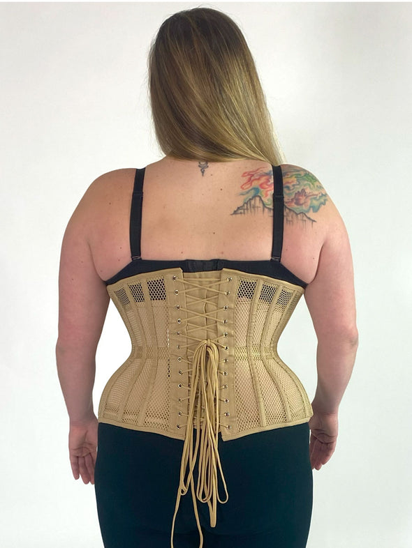 Back lace up view of plus size curvy model wearing the 426 longline mesh waist training beige corset with a black bra and black leggings