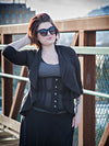 Woman wearing a cs426 hourglass curve black corset and black outfit with sunglasses on a bridge