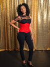 Model with dark curly hair wearing a festive Holiday red corset with a sheer top and black pants
