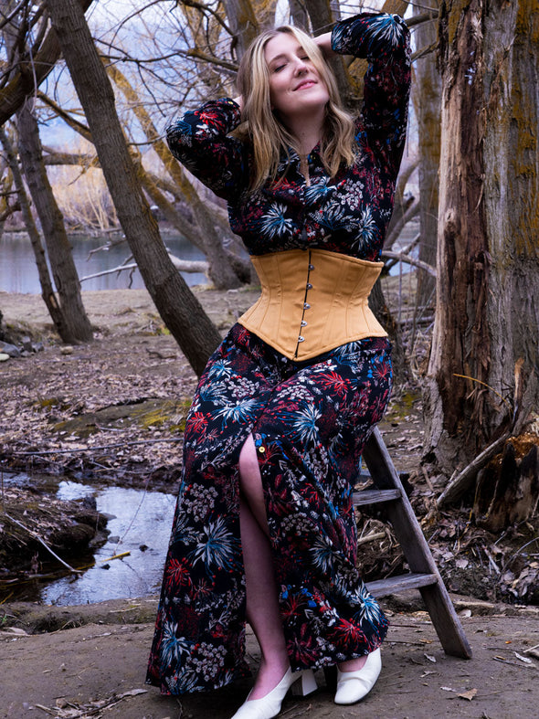 Model wearing a long floral maxi dress with a beige cotton waspie corset