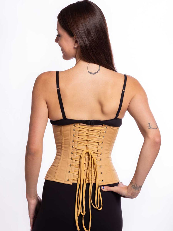 cute model wearing a plus size 305 beige cotton steel boned waist training corset with a black bra and leggings back lace up corset  view