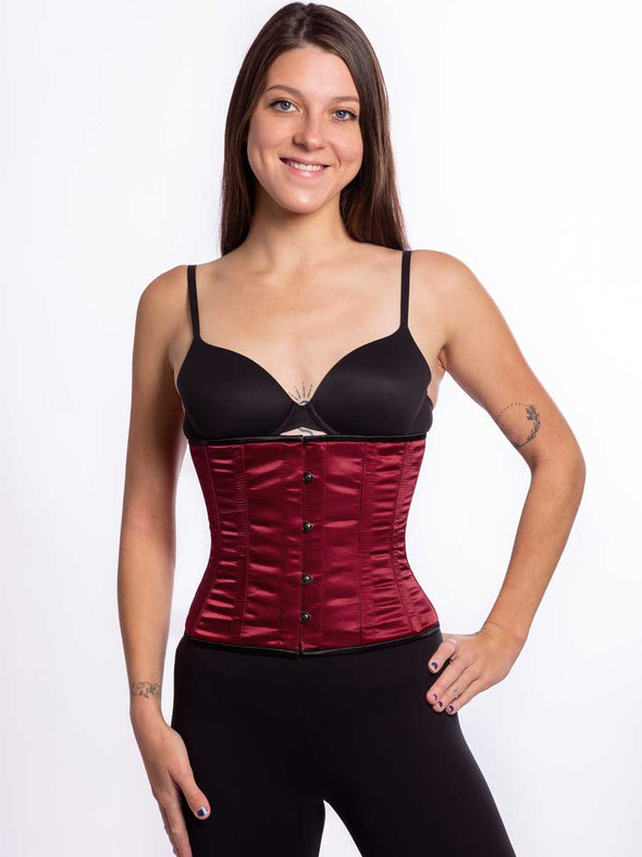 Cute athletic build model wearing a modern curve corset in wine color with black leggings and black bra