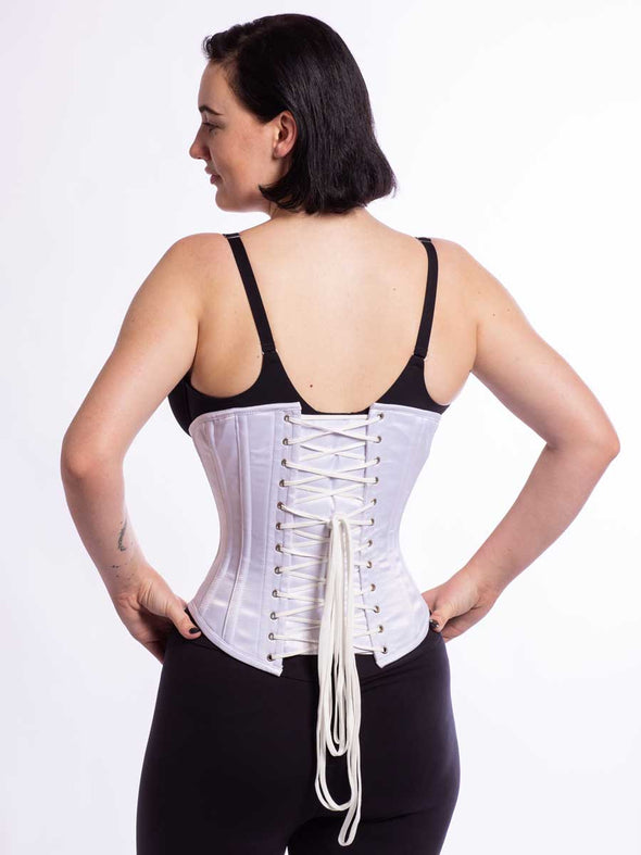 Model with feminine curves wearing the cs 345 corset in silky white satin back lace up view