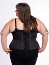 cute curvy plus size model wearing a bra and leggings and a black cotton everyday corset for waist training over the top back lace up corset view