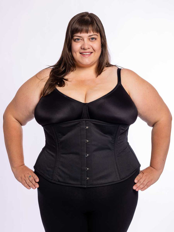 cute curvy plus size model wearing a bra and leggings and a black cotton everyday corset for waist training over the top
