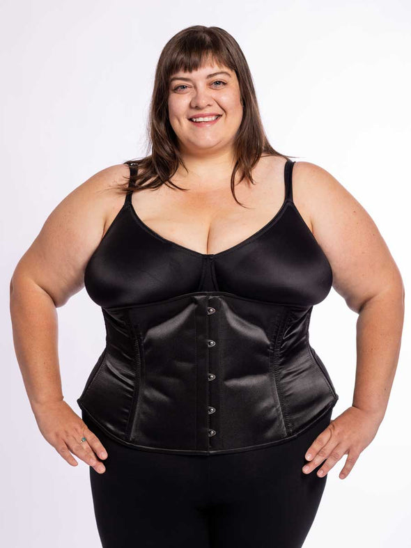 cute corset model wearing black bra and leggings with a  black satin cs 411 longline full figure plus size corset, front