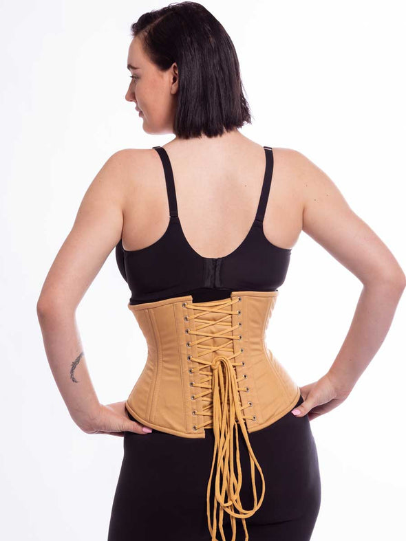 model wearing the beige cotton cs411 facing away showing the back lace up detail with hands on hips