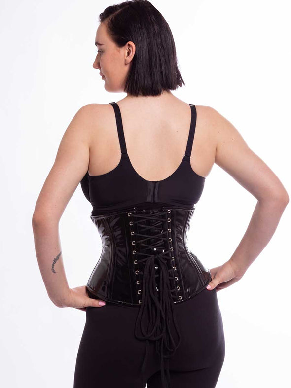 Black Shiny Latex PVC corset on cute model back facing showing the back lace up detail hands on hips
