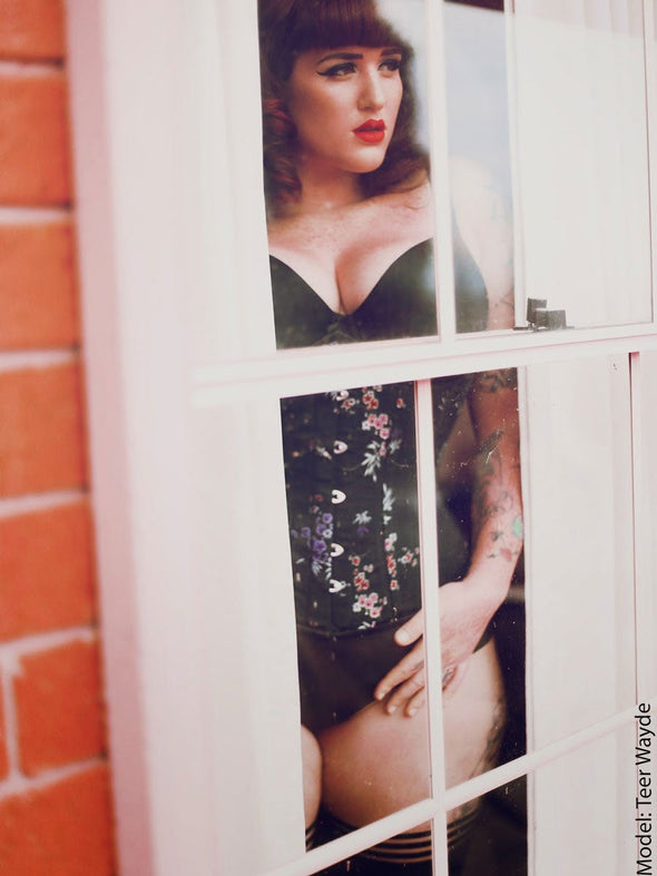 Model Teer Wayde in the cute 426 long multi colored brocade corset with bra top and stockings looking through a window