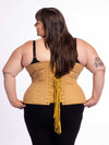 curvy plus size model wearing a beige cotton corset for fashion or waist training over black leggings and a black bra showing the back lace up view