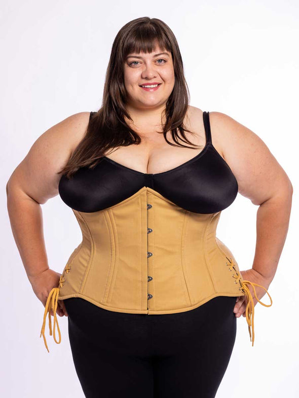 curvy plus size model wearing a beige corset for waist training and fashion over black leggings and bra