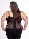 cute curvy plus size corset model wearing a shimmering maroon corset over a black bra and leggings back lace up corset view