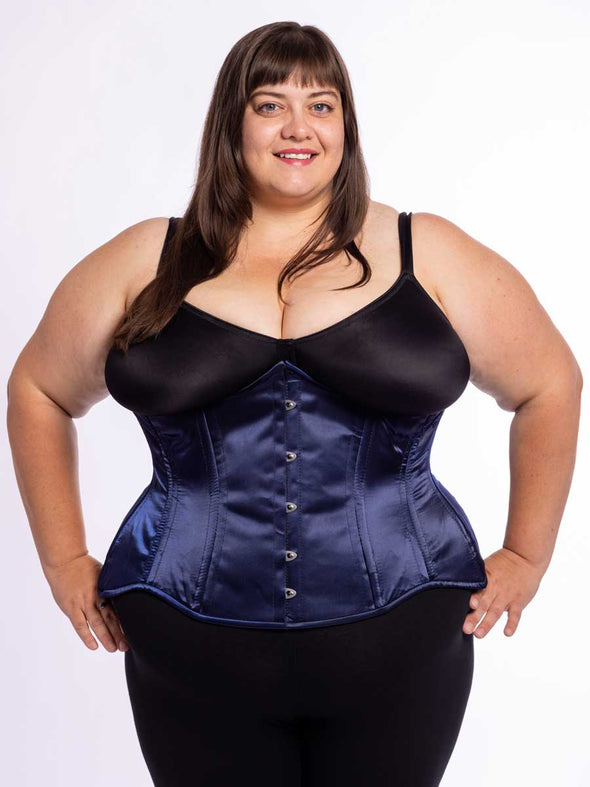 curvy plus size model wearing a black bra and leggings with a navy satin longline corset