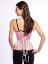 smiling cute corset model wearing an hourglass curve pink satin corset with hip ties over a black bra and leggings back lace up corset view
