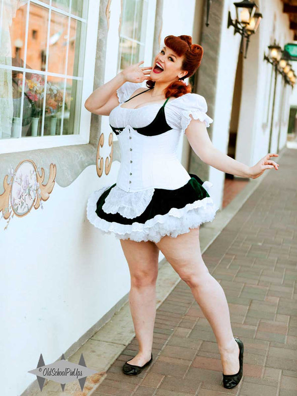 cute curvy model wearing a short skirt and white blouse with a white hourglass curve corset over the outfit