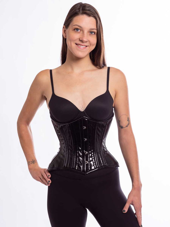 Smiling model wearing the cs426 hourglass curve corset in shiny black latex pvc front busk view