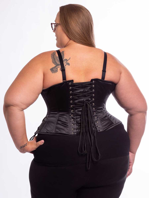 Curvy plus size model wearing black leggings and black bra with the black satin cs426 with hip ties showing the back lace up detail