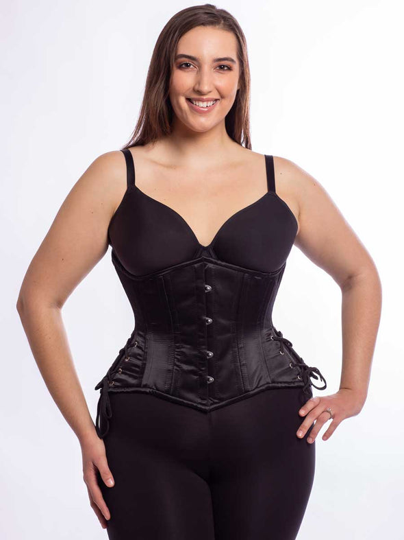 Model wearing our 426 with hip ties steel boned waist training corset in black satin with leggings and a black bra