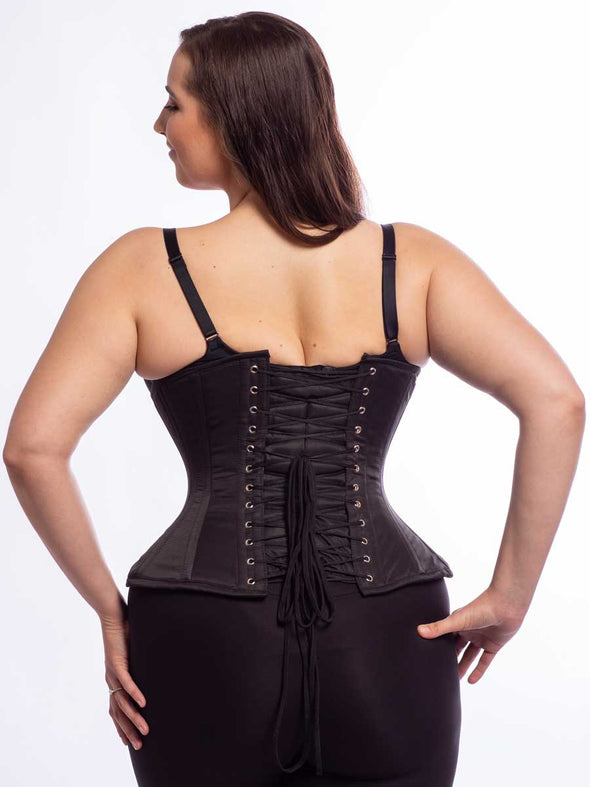 Cute model wearing the extreme curve cs 479 corset in black matte satin back lace up view