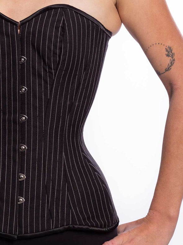 Front detail view of a Cute model wearing a timeless black pinstripe corset top with black leggings