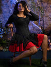 Seated model wearing the cs530 overbust corset top over a black shirt and red and black skirt