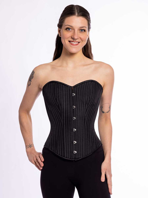 cute corset model wearing an overbust strapless corset top in a black pinstripe fabric with black leggings