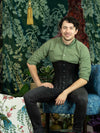 male model in jeans and a shirt wearing the black leather 701 corset sitting in a chair