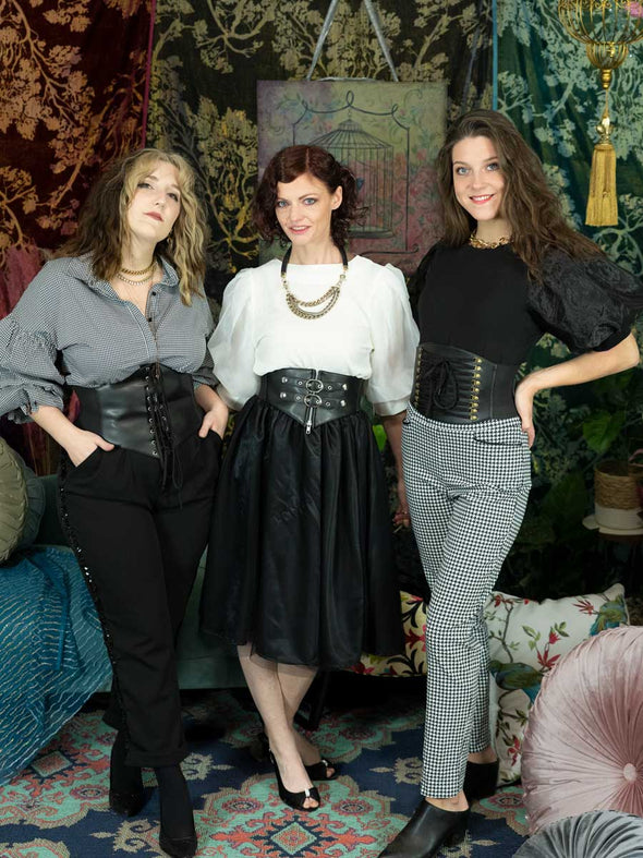 Three models all in different styles of corset belts in fashion attire