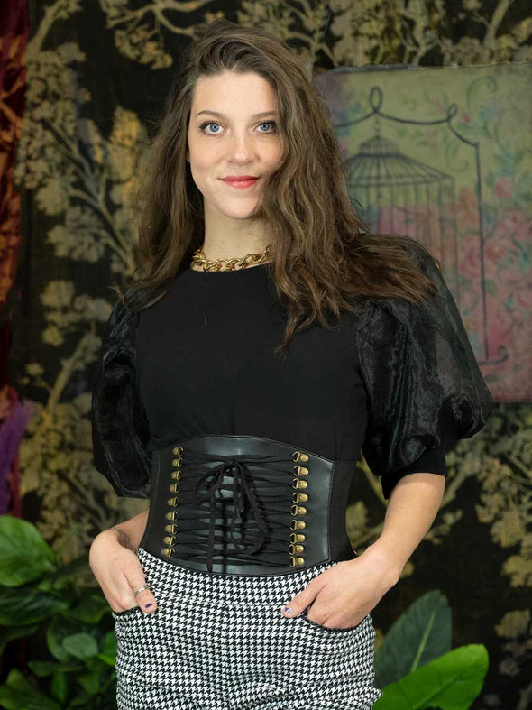 Cute Woman wearing checked pants and a black puffy shirt with a black faux lace up corset belt