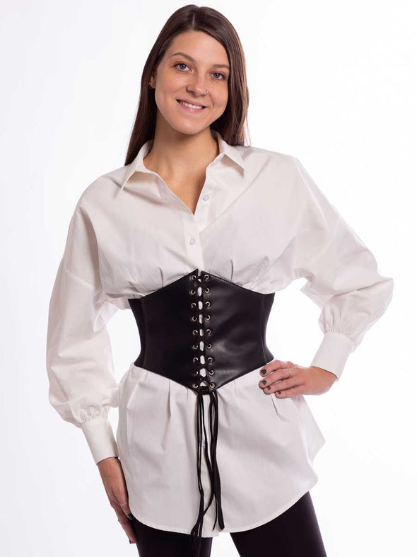 Woman wearing a white tunic and black leggings with a black laced corset on top
