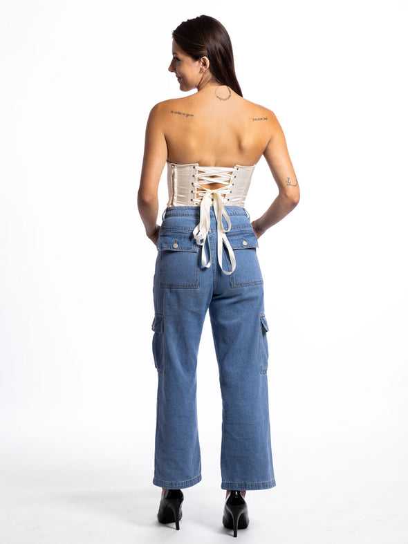 Back lace up view of a Cute model wearing an Ivory fashion corset top worn with jeans and high heeled shoes