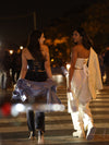 Model wearing a black chiffon and satin cropped fashion corset top with dark jeans and a washed jean jacket with a friend wearing an ivory celebrity corset top with Ivory pants and jacket