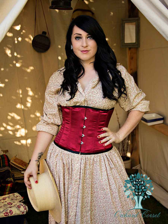 model with hat wearing the cs305 corset in wine over a cute floral dress
